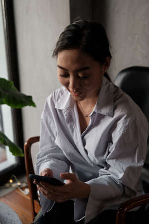 Young Asian woman using smart phone for transfer money, business, online shopping, financial, internet banking in coffee shop.の写真素材