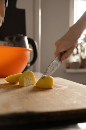 Cooking. Close-up of a kitchen knife in female hands. A woman cuts vegetables for soup. A knife cuts potatoes on a wooden boardの写真素材
