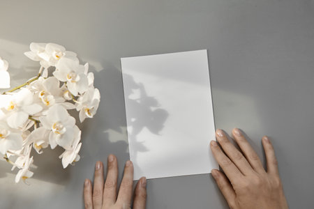 Hands are holding an empty white A5 form on a gray background. Layout top viewの写真素材