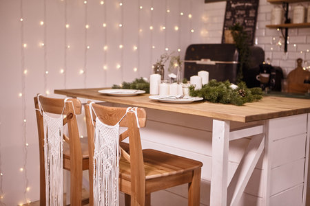 Beautiful white kitchen. Winter holidays composition..Christmas kitchen decor and copy space. Rustic cuisine at Christmas. Kitchen island table with festive table setting.の写真素材