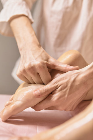 Close up reflexology foot massage. Professional therapist giving leg and foot massage to a woman in spa. Female massage therapist massaging clients legs. Body relaxation and skin careの写真素材