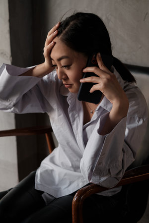 Attractive smiling young asian woman relaxing in cafe, working on laptop computer, talking on mobile phoneの写真素材