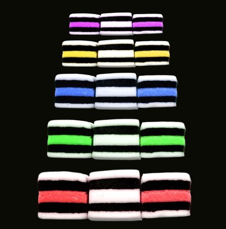Five lines of brightly coloured  liquorice allsorts on a black background.のeditorial素材
