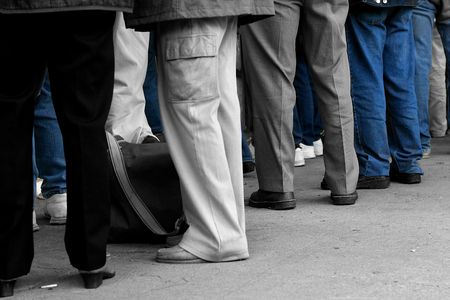 Peoples legs, wearing trousers and jeans. Desaturated with only the jeans saturated.