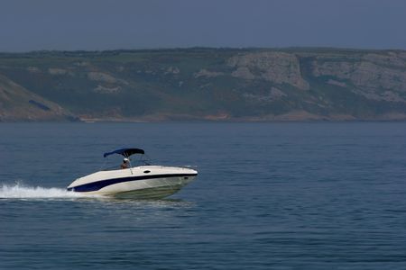 Man in a blue and white speed boat on the sea.