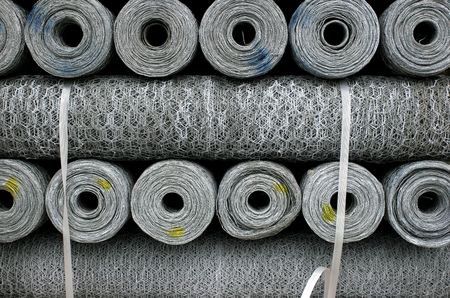 Stacked rolls of single strand metal chicken wire of different thicknesses, marked by yellow and blue paint..の写真素材