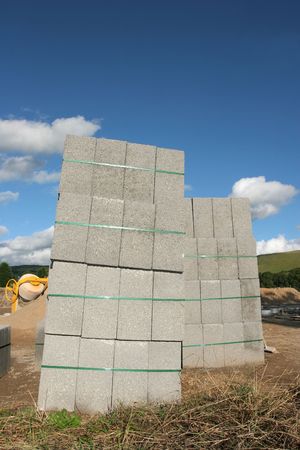 Stacks of concrete blocks on a building construction site, against a blue sky.