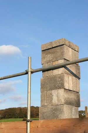 Concrete blocks stacked on scaffolding against a blue sky.
