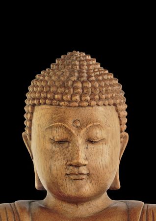 Wooden Buddha with eyes closed in prayer, over black background.の写真素材