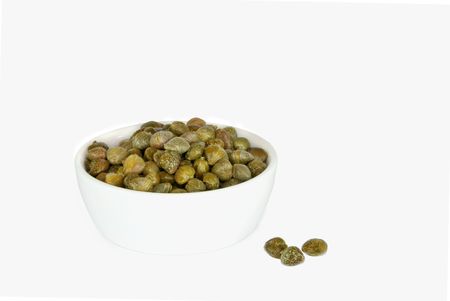 Capers in a china bowl with three loose capers, over white background.の写真素材