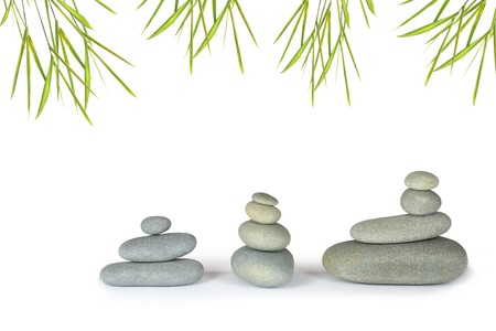 Zen abstract of grey spa stone massage pebbles in perfect balance, with bamboo leaf grass, over white background.の写真素材