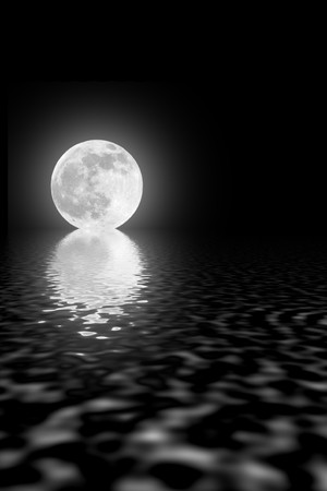 Abstract of a full moon on the spring equinox with reflection over rippled water against a black sky.の写真素材