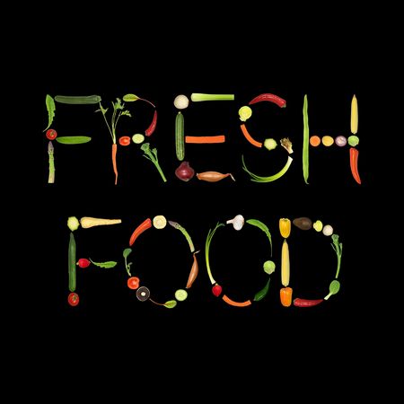 Vegetable selection spelling the words fresh food, over black background.の写真素材