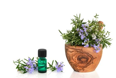  Rosemary and thyme herb leaf sprigs with flowers in an olive wood mortar with pestle and an aromatherapy essential oil glass bottle, over white background.の写真素材