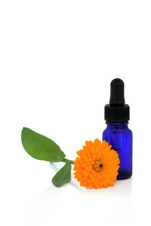 Calendula flower and aromatherapy essential oil glass bottle, over white background.の写真素材