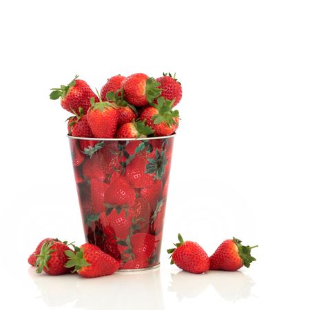 Strawberries in a metal container with strawberry design, over white  background.の写真素材