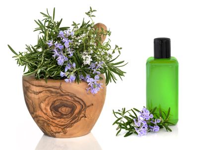  Rosemary and thyme herb leaves and flowers in an olive wood mortar with pestle with an aromatherapy bottle and floral leaf sprig, over white background.の写真素材