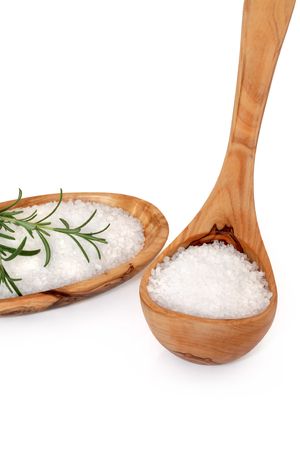 Sea salt in an olive wood ladle and bowl with a rosemary herb leaf sprig, over white background.の写真素材