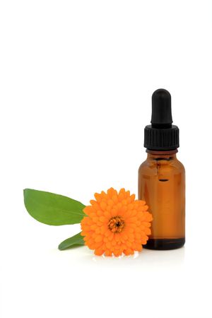 Marigold flower and aromatherapy essential oil glass dropper bottle, over white background.の写真素材
