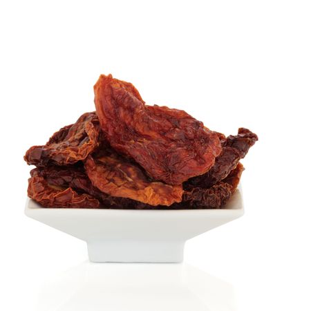Sun dried tomatoes in a white porcelain dish isolated over white background.の写真素材