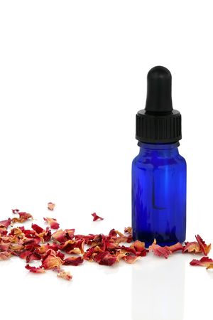 Aromatherapy essential oil glass bottle with dried   rose petals, isolated over white background.の写真素材