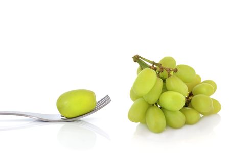 Bunch of green grapes with one on the end of a stainless steel fork, isolated over white background with reflection.の写真素材