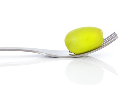 Green grape on a stainless steel metal fork, isolated over white background with reflection.の写真素材