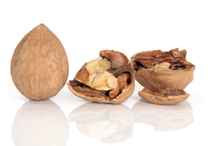 Walnut kernels whole and cracked open with shells, isolated over white background.