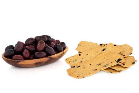 Black olives in an olive wooden bowl with dried olive crackers, isolated over white background.の写真素材