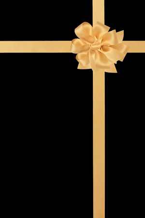 Gold satin ribbon with bow isolated over black background.の写真素材