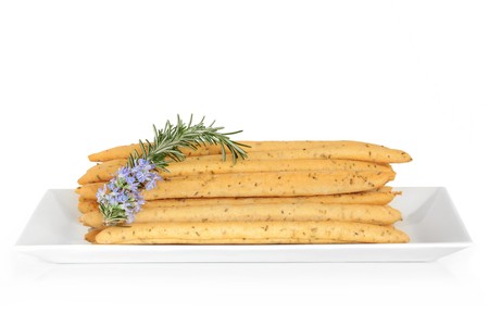 Rosemary flavoured bread sticks with leaf and flower herb sprig in a porcelain dish, isolated over...