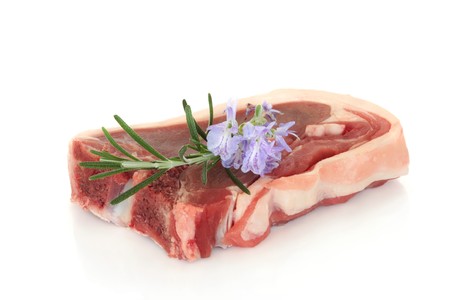 Lamb chop with fresh rosemary herb flower and leaf sprig isolated over white background.の写真素材