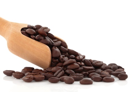 Coffee beans spilling out from a wooden scoop, isolated over white background.の写真素材