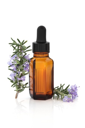Rosemary herb leaf and flower sprigs with aromatherapy essential oil glass bottle, isolated over white background with reflection.の写真素材