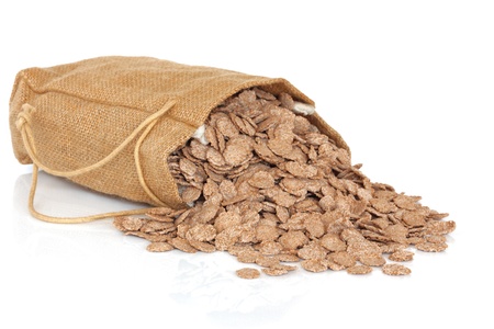 Bran flakes in a jute bag and scattered, isolated over white background.の写真素材