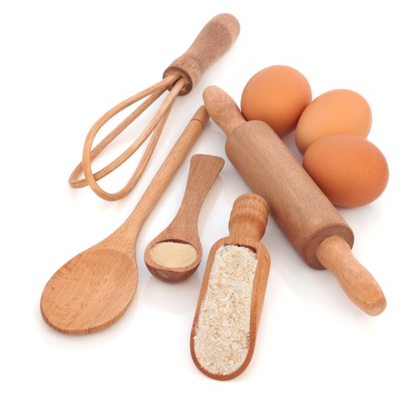  Baking equipment and ingredients, with wholegrain flour, yeast and eggs, with rustic natural wooden spoons, scoop, whisk and rolling pin, isolated over white background.の写真素材