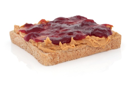 Peanut butter and raspberry jam on brown wholemeal bread, over white background.の写真素材