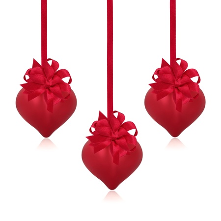 Valentine heart red baubles with ribbon and bow decorations forming a border, isolated over white background with copy space.の写真素材