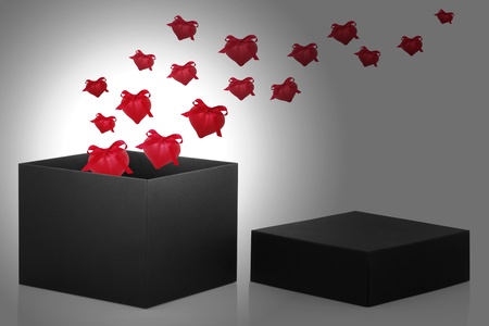 Black gift box open with lid to one side and heart shaped baubles with ribbons and bows, isolated over white background.の写真素材