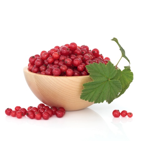 Redcurrant fruit in a beech wood bowl with leaf sprig and scattered, isolated over white background.の写真素材