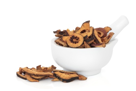 Dried bitter orange fruit slices in a porcelain mortar with pestle and scattered, isolated over white background. Used in traditional chinese herbal medicine. Zhi Ke. Fructus citri aurantii.の写真素材