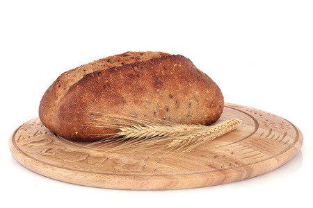 Olive bread with wheat ears on a carved rustic wooden bread board, isolated over white background.の写真素材