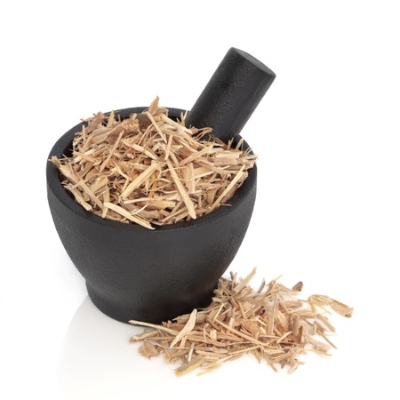 Ginseng in a black granite mortar with pestle and scattered, over white background.の写真素材