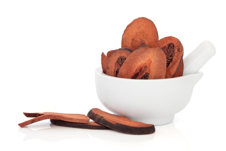 Dried quince fruit used in chinese herbal medicine in a porcelain mortar with pestle and scattered isolated over white background.  Mu gua. Cortex montan radicusの写真素材