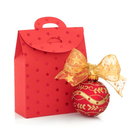 Christmas gift bag in red with star design with decorated sparkling bauble and gold ribbon isolated over white background.の写真素材