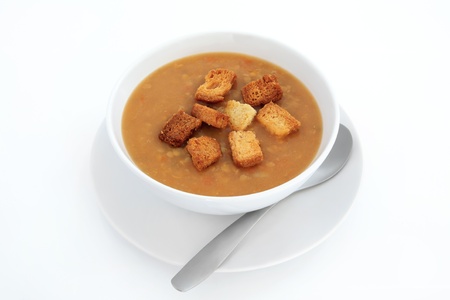 Lentil soup with croutons in a white porcelain bowl with plate and spoon isolated over white background.の写真素材