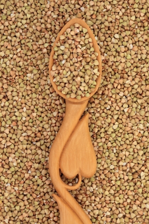 Buckwheat in a heart shaped wooden spoon and forming a background の写真素材