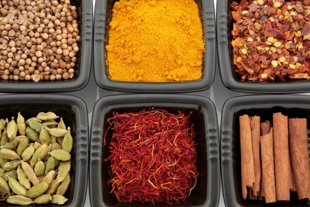 Spice selection of cardamom pods, saffron, cinnamon sticks, coriander seed, turmeric and chili flakes in black dishes  Selective focus の写真素材