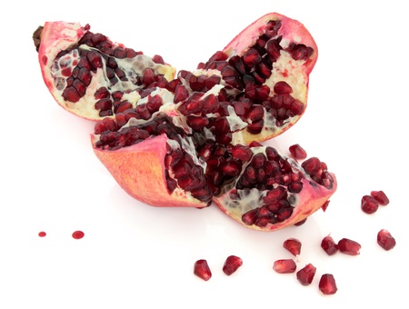 Pomegranate fruit cut open to expose red seeds over white background の写真素材