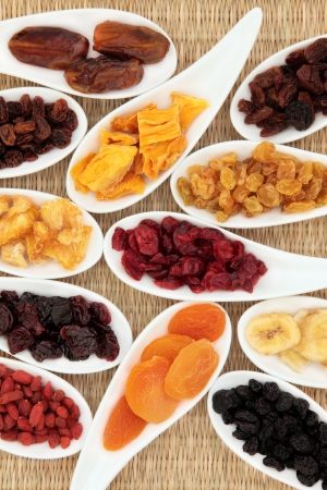 Dried fruit selection in white porcelain dishes over wicker background の写真素材